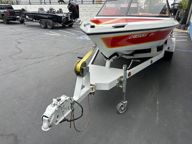 Slide: The Image of 1988 Malibu Skier boat on trailer, red and white design, parked in lot. - 3