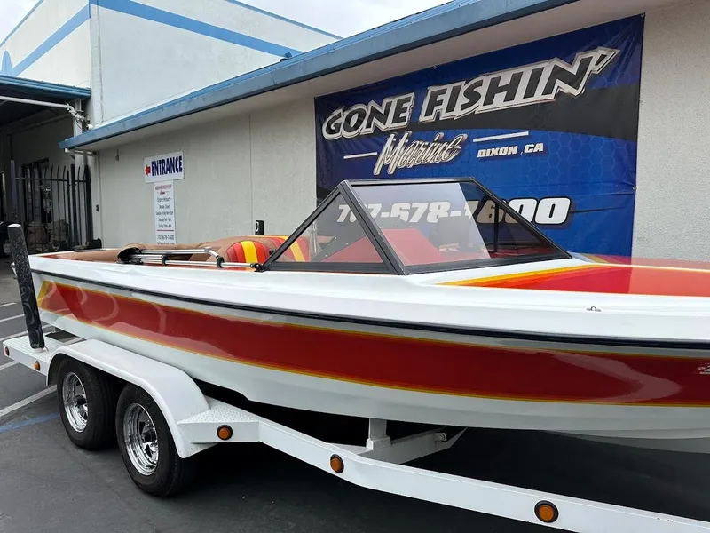 Slide: The Image of 1988 Malibu Skier boat on trailer, red and white design, parked outside a building. - 5