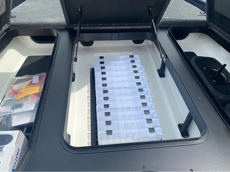 Slide: The Image of Open storage compartment in 2025 Skeeter ZXR 21 boat, featuring organized tackle boxes. - 11