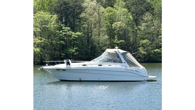 Slide: The Image of 2002 Sea Ray 340 Sundancer yacht on a serene lake with lush green trees. - 0