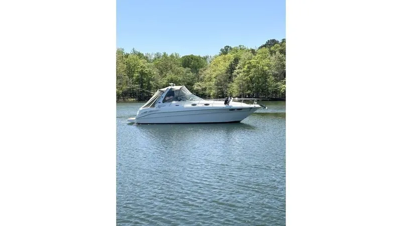 Slide: The Image of 2002 Sea Ray 340 Sundancer boat on calm water, surrounded by lush greenery. - 1