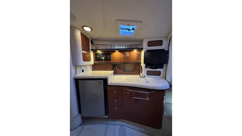 Slide: The Image of 2002 Sea Ray 340 Sundancer interior kitchen with wood cabinets, sink, and mini fridge. - 11