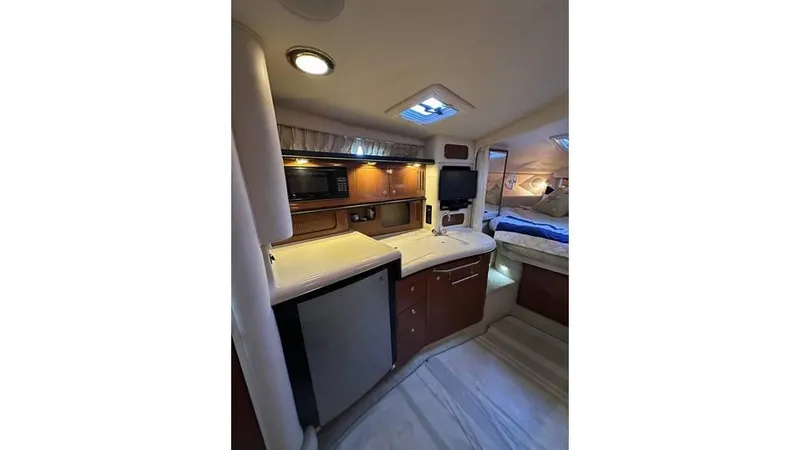 Slide: The Image of 2002 Sea Ray 340 Sundancer interior with kitchenette and cozy sleeping area. - 12