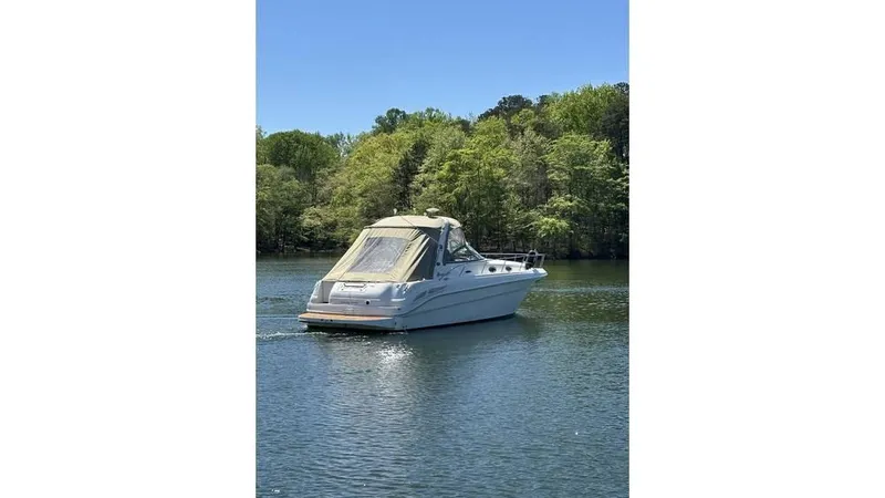 Slide: The Image of 2002 Sea Ray 340 Sundancer boat cruising on a serene lake with lush green trees. - 2