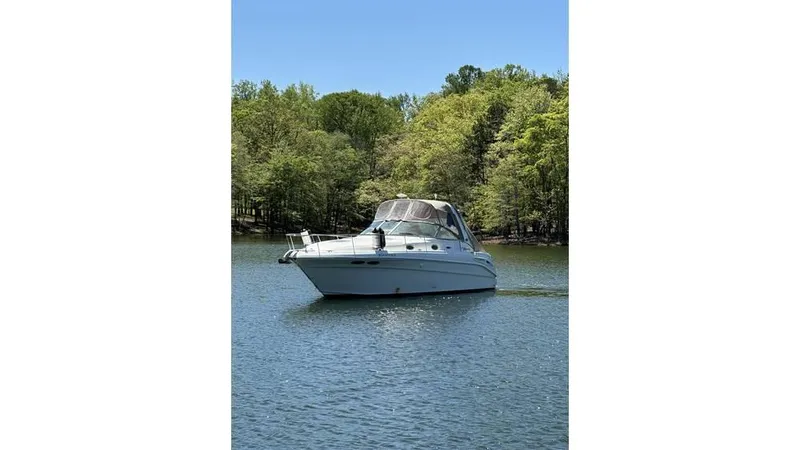 Slide: The Image of 2002 Sea Ray 340 Sundancer boat on a serene lake with lush green trees. - 5