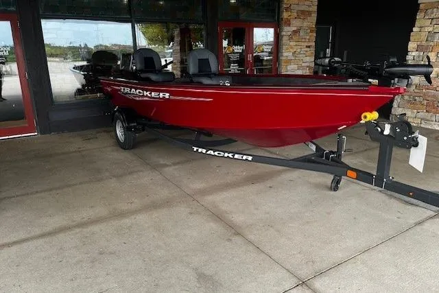 Slide: The Image of Red 2025 Tracker Super Guide V-16 T boat on trailer, parked outside a building. - 8