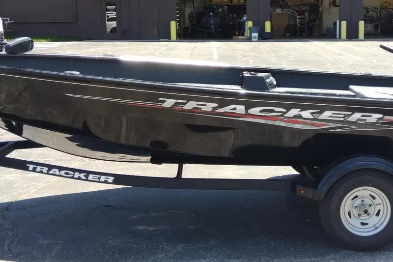 The Image of 2025 Tracker Super Guide V-16 T boat on trailer, black exterior, parked outdoors. - 0