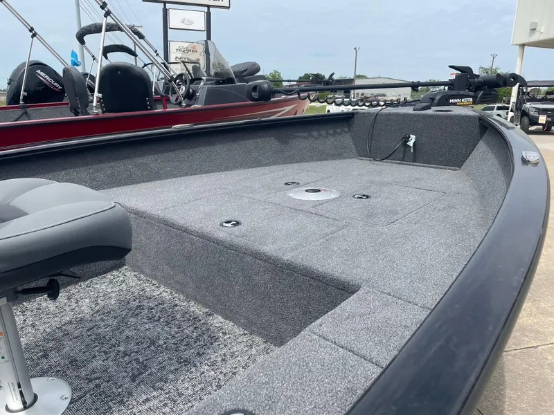 Slide: The Image of 2025 Tracker Super Guide V-16 T boat interior with gray seating and carpeted deck. - 9