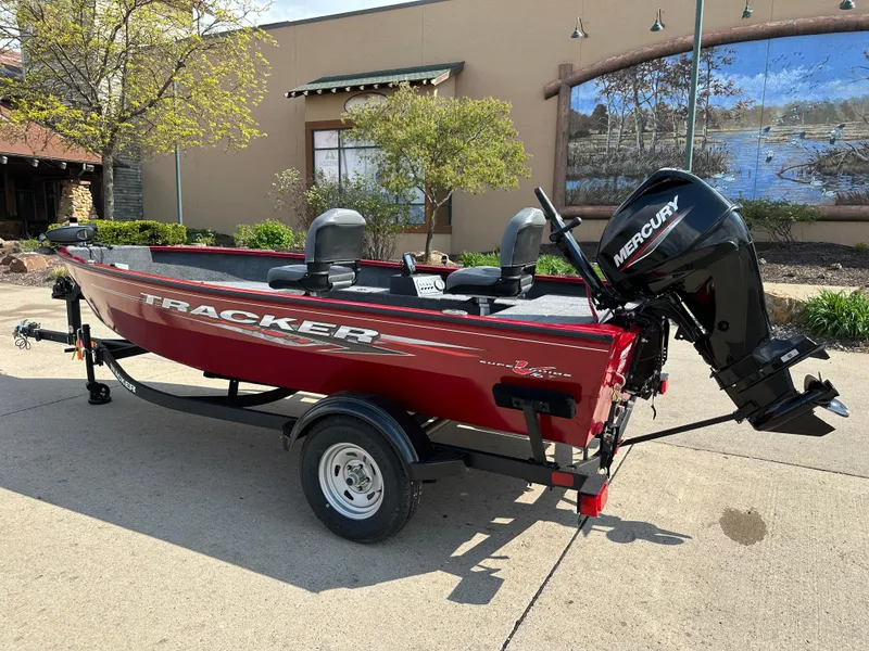 Slide: The Image of 2025 Tracker Super Guide V-16 T boat with Mercury motor on trailer, parked outdoors. - 2