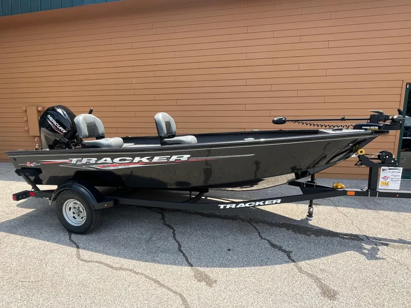 The Image of 2025 Tracker Super Guide V-16 T fishing boat on trailer, parked outdoors. - 0