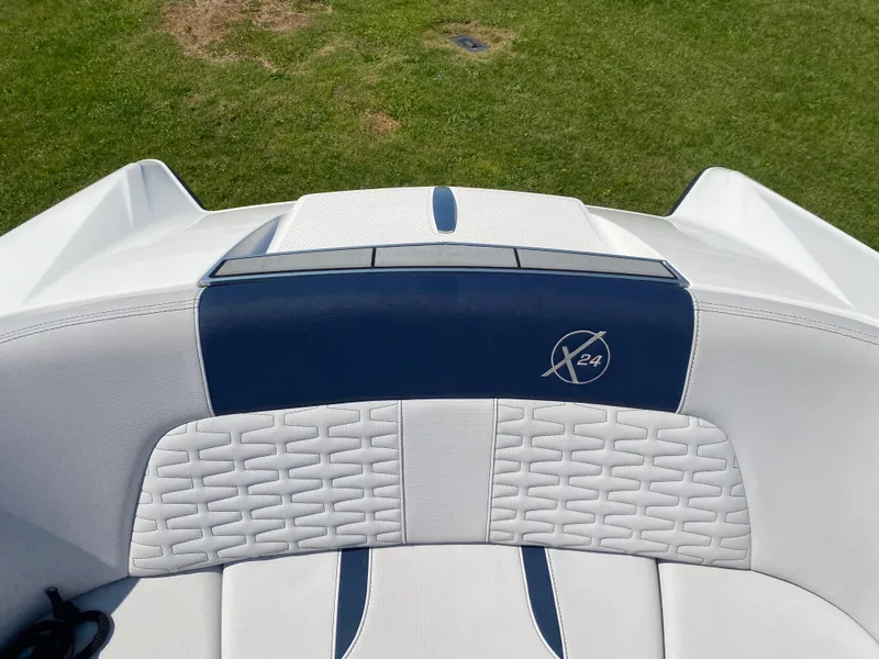 Slide: The Image of MasterCraft X24 2021 boat interior with white and blue seating on grass background. - 14