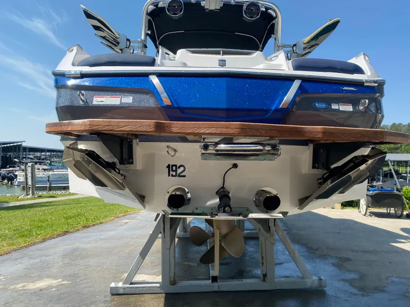 Slide: The Image of 2021 MasterCraft X24 boat on stand, rear view showing propeller and blue detailing. - 2