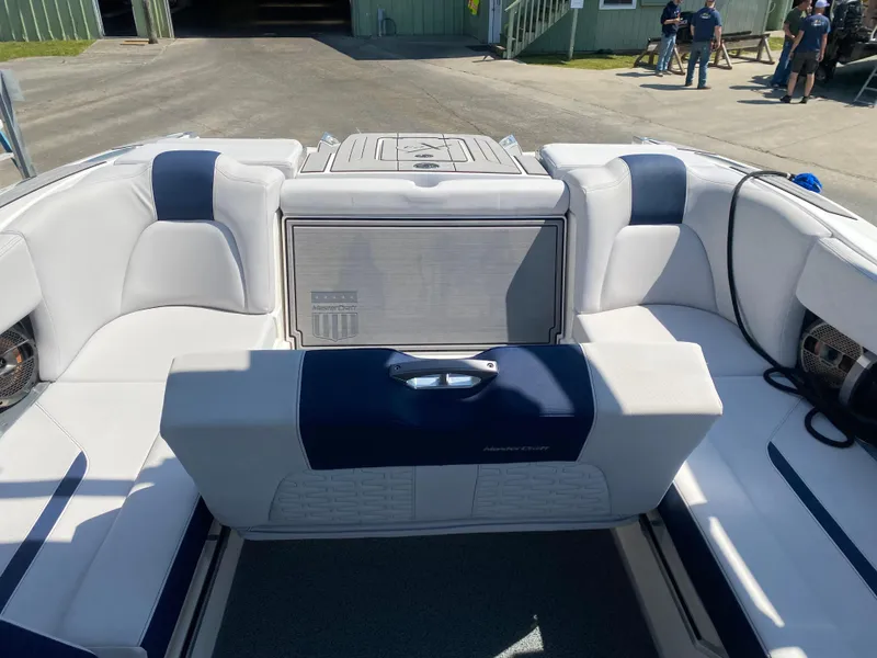 Slide: The Image of 2021 MasterCraft X24 boat interior with white and navy seating, docked outdoors. - 4