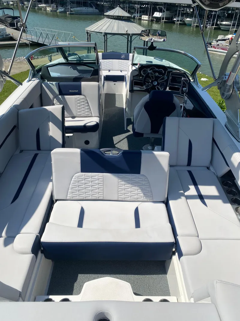 Slide: The Image of 2021 MasterCraft X24 boat interior with luxurious seating and modern dashboard, docked by the water. - 6