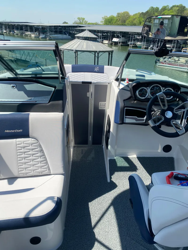 Slide: The Image of 2021 MasterCraft X24 boat interior with modern dashboard and seating, docked at marina. - 8