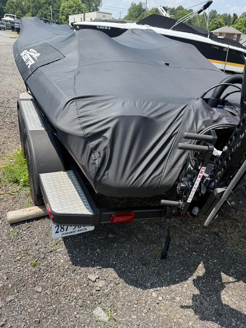 Slide: The Image of 2023 Skeeter ZXR20 boat covered on a trailer, parked on gravel. - 27