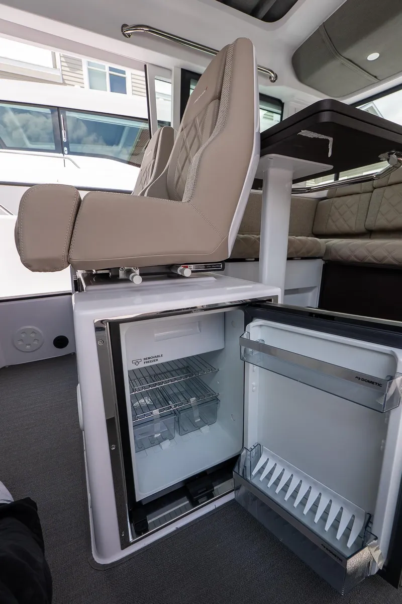Slide: The Image of 2024 Axopar Cross Cabin interior with open mini fridge and seating area. - 35