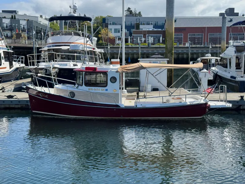 Slide: The Image of 2016 Ranger Tugs R-21EC boat docked in a marina, featuring a red and white exterior. - 0