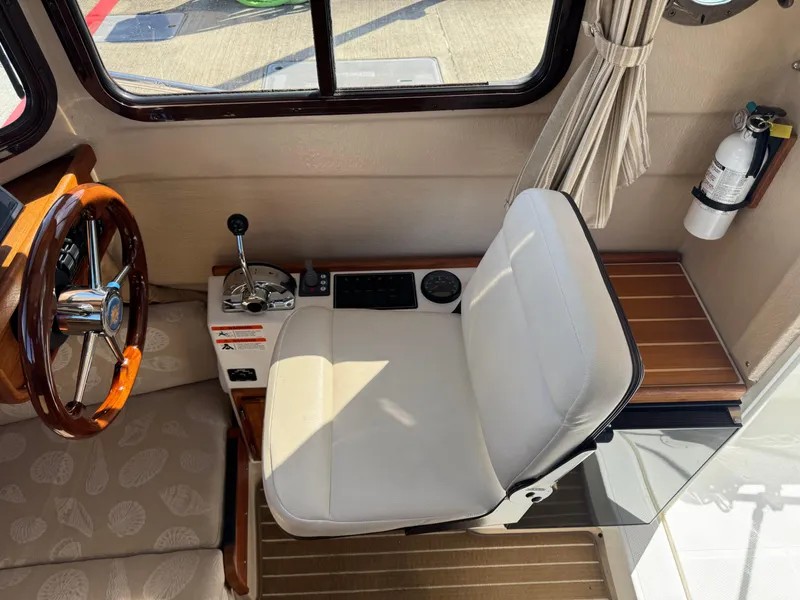 Slide: The Image of 2016 Ranger Tugs R-21EC helm with white seat, wooden steering wheel, and control panel. - 12