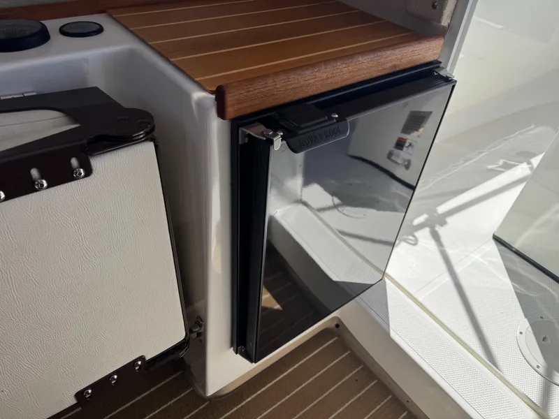 Slide: The Image of 2016 Ranger Tugs R-21EC interior with compact fridge and wooden accents. - 16