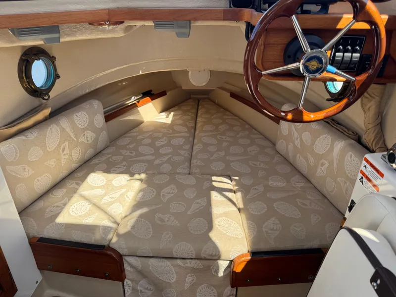 Slide: The Image of 2016 Ranger Tugs R-21EC cabin interior with patterned cushions and wooden steering wheel. - 22