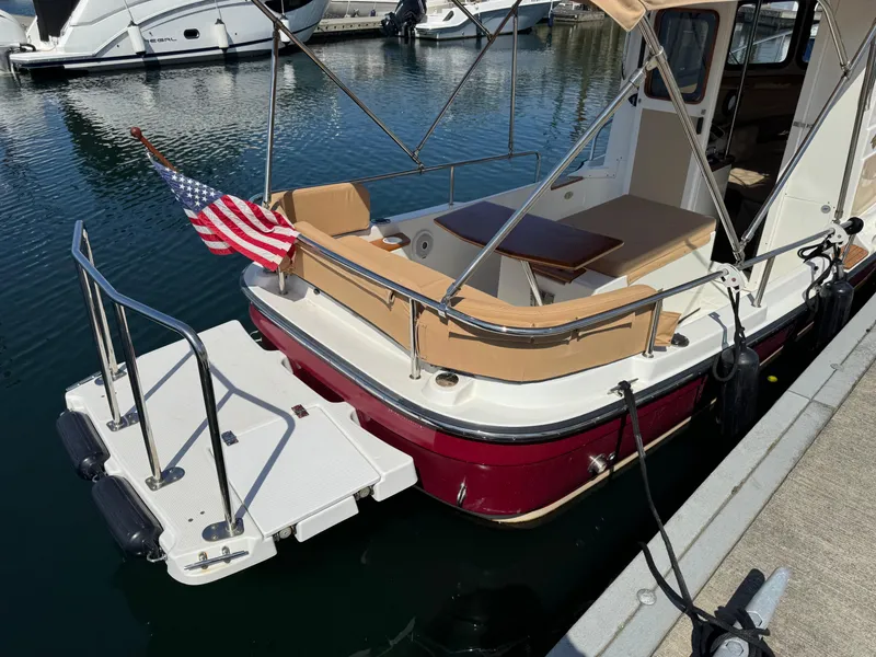 Slide: The Image of 2016 Ranger Tugs R-21EC boat docked, featuring a red hull and American flag. - 7