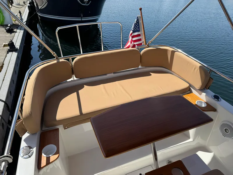 Slide: The Image of 2016 Ranger Tugs R-21EC boat interior with cushioned seating and wooden table. - 8