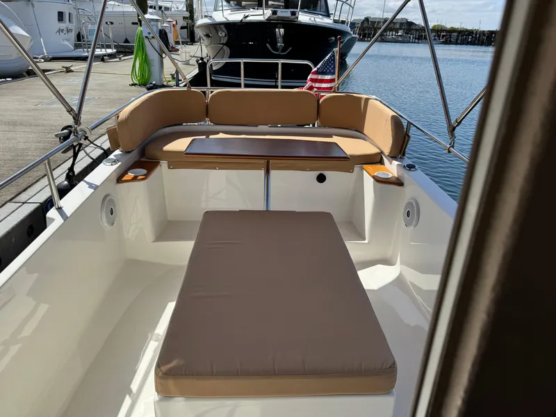 Slide: The Image of 2016 Ranger Tugs R-21EC boat interior with cushioned seating and table, docked at marina. - 9