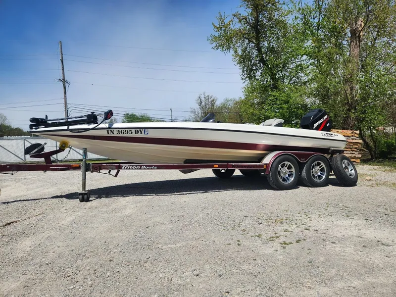 Slide: The Image of 2000 Triton TR21 boat on trailer, parked outdoors, with trees in the background. - 1
