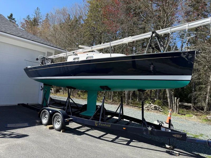 Slide: The Image of 2014 Tartan Fantail sailboat on trailer, parked near a garage, surrounded by trees. - 0