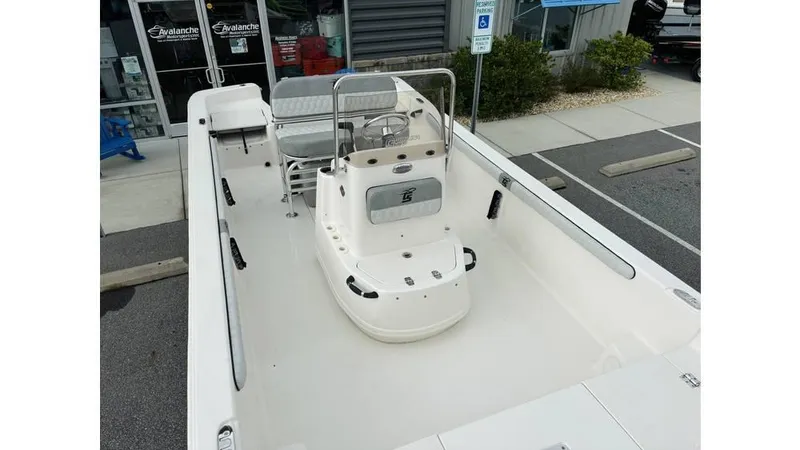 Slide: The Image of 2025 Carolina Skiff 21 LS boat, spacious deck, center console, parked near a building. - 14