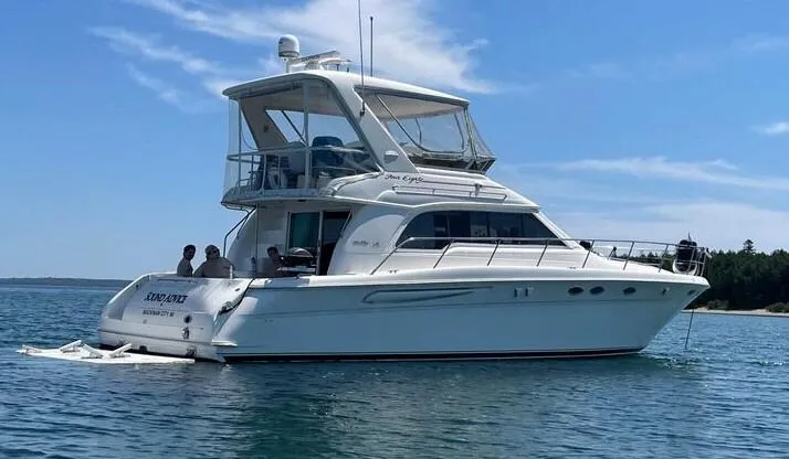 Slide: The Image of 1998 Sea Ray 480 Sedan Bridge yacht on calm water under clear blue sky. - 0