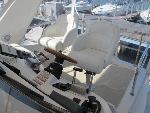 Slide: The Image of 1998 Sea Ray 480 Sedan Bridge helm with white captain chairs and control panel. - 17