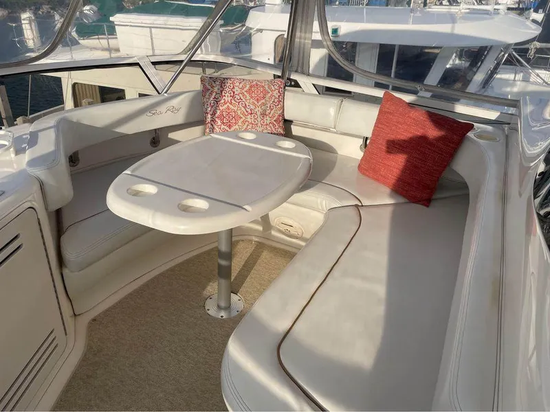 Slide: The Image of 1998 Sea Ray 480 Sedan Bridge interior with cushioned seating and table. - 18