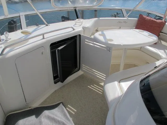 Slide: The Image of 1998 Sea Ray 480 Sedan Bridge yacht interior with seating, table, and open mini-fridge. - 19