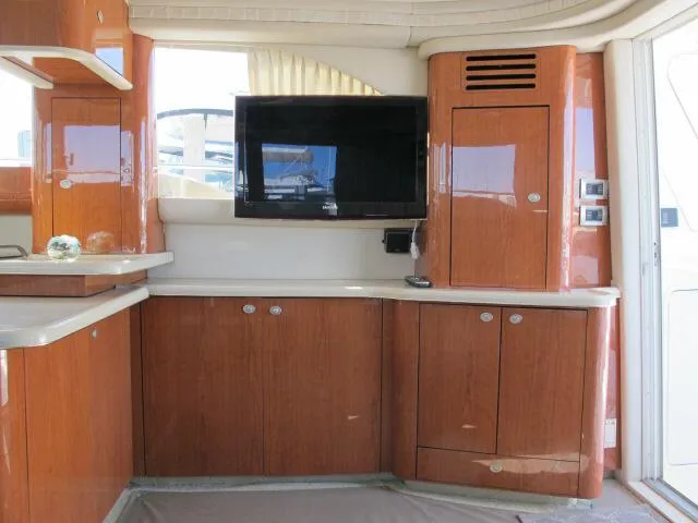 Slide: The Image of Interior of 1998 Sea Ray 480 Sedan Bridge with wood cabinetry and mounted TV. - 3