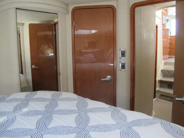 Slide: The Image of Interior of 1998 Sea Ray 480 Sedan Bridge, featuring a cozy bedroom with wooden doors. - 7