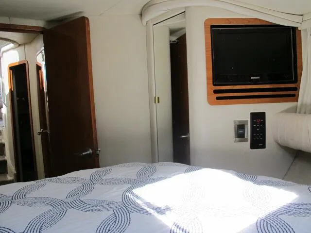Slide: The Image of Interior of 1998 Sea Ray 480 Sedan Bridge with bed, TV, and wooden accents. - 9