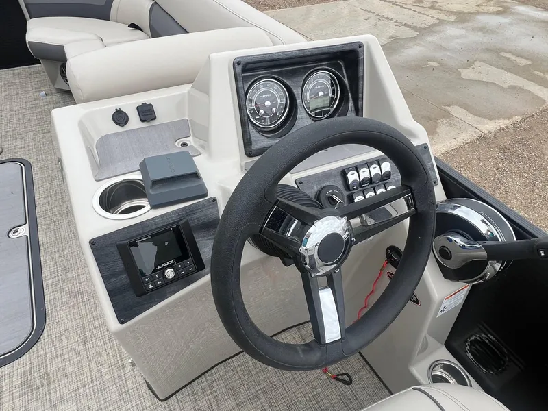 Slide: The Image of 2022 Harris Cruiser 230 boat dashboard with steering wheel, gauges, and audio controls. - 12
