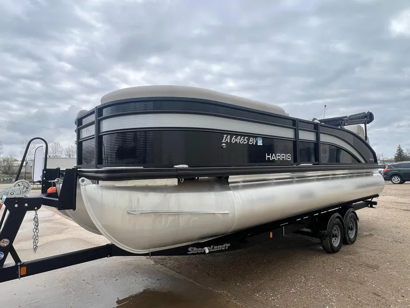 Slide: The Image of 2022 Harris Cruiser 230 pontoon boat on trailer under cloudy sky. - 2