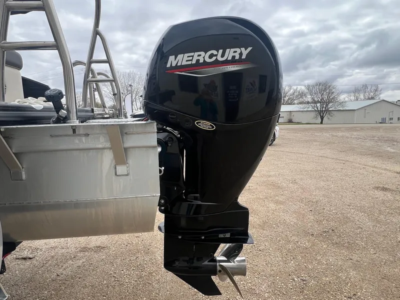 Slide: The Image of 2022 Harris Cruiser 230 with Mercury outboard motor, parked outdoors on a cloudy day. - 6