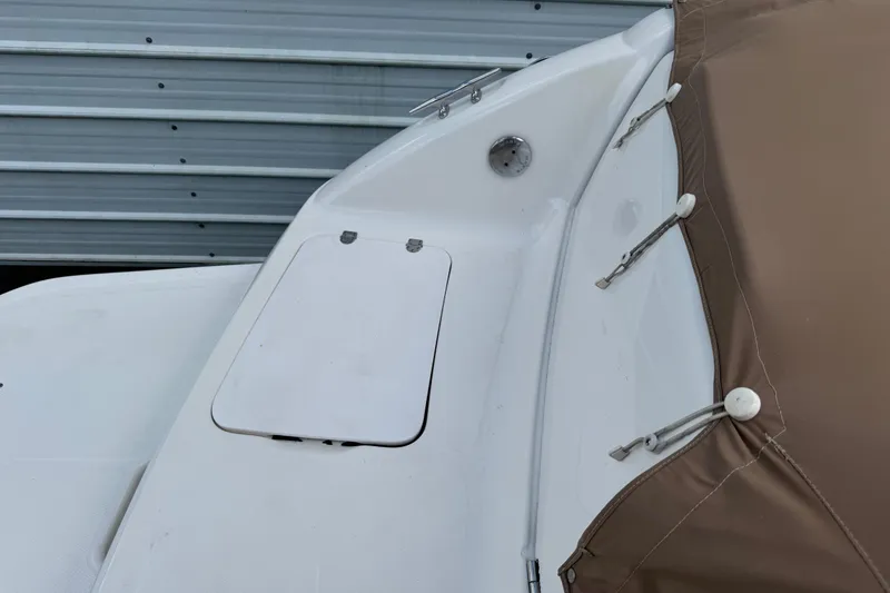 Slide: The Image of 2004 Chaparral 260 SSi boat with brown cover and white deck, near metal siding. - 1