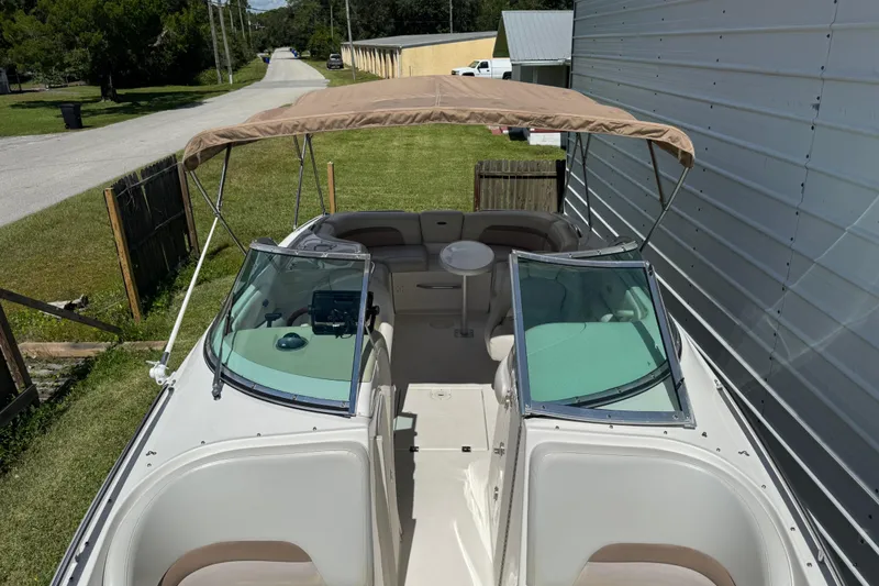 Slide: The Image of 2004 Chaparral 260 SSi boat with canopy, parked beside a metal building. - 23