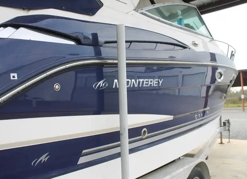 Slide: The Image of 2013 Monterey 260 SCR boat, blue and white exterior, docked on a trailer. - 2