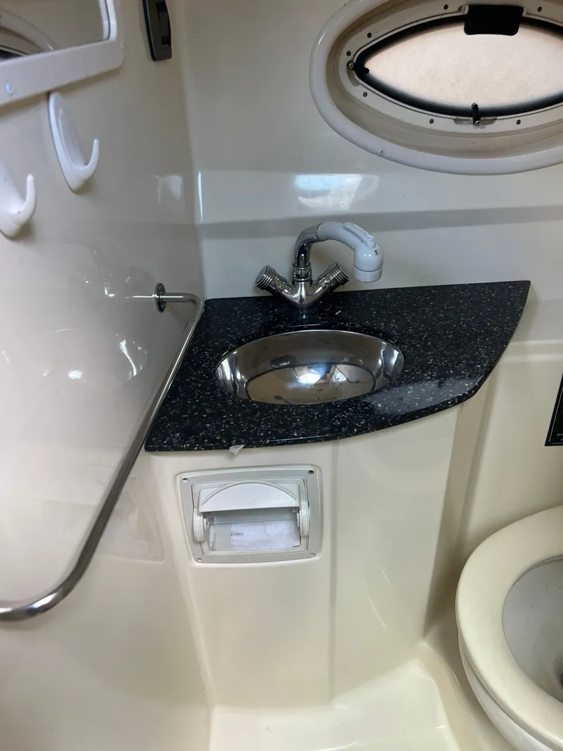 Slide: The Image of 2013 Monterey 260 SCR boat bathroom with sink, faucet, and porthole window. - 29