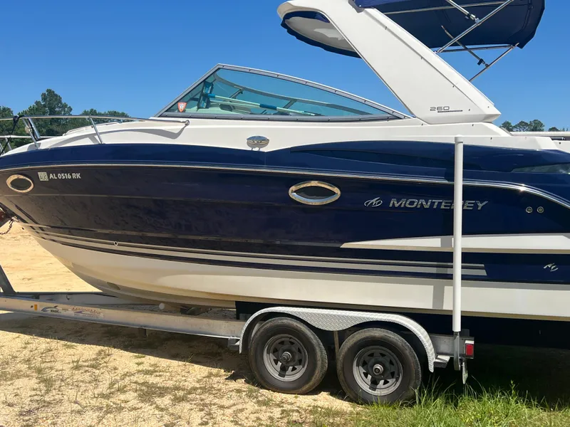 Slide: The Image of 2013 Monterey 260 SCR boat on trailer, blue and white design, parked on sandy ground. - 5