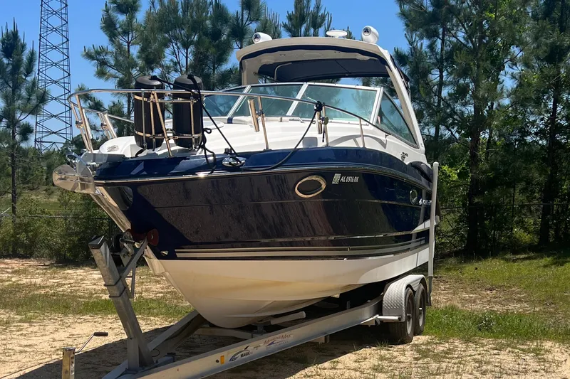 Slide: The Image of 2013 Monterey 260 SCR boat on trailer, surrounded by trees, under clear blue sky. - 6