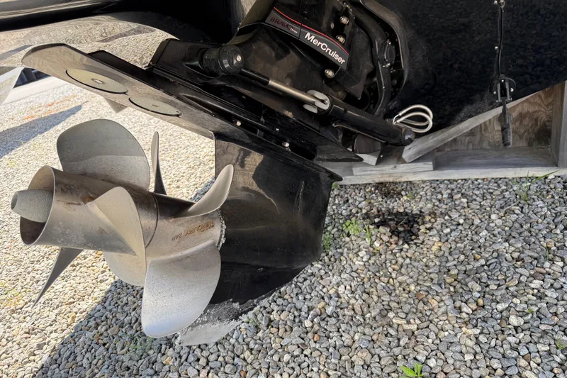 Slide: The Image of Close-up of a 2015 Rinker 246 Bowrider boat propeller on gravel surface. - 10