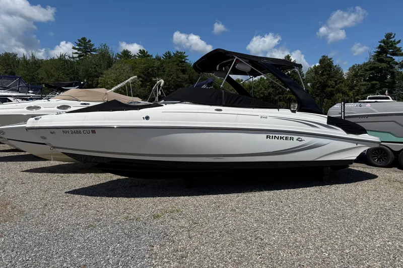 Slide: The Image of 2015 Rinker 246 Bowrider boat parked on gravel, surrounded by trees and other boats. - 9