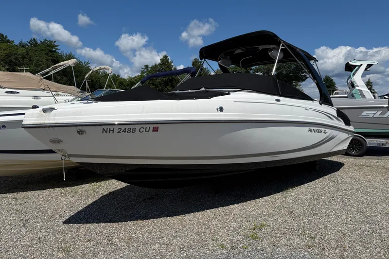Slide: The Image of 2015 Rinker 246 Bowrider boat on display, parked on gravel, under a clear blue sky. - 12
